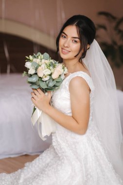 Mutlu gelin gelinlik içinde oturup gülümsedi. Bridde ve buketi