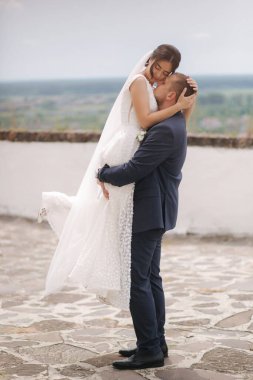 Damat ve gelin şehir manzarasının önünde duruyor.