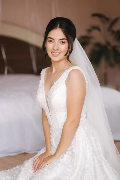 Šťastná nevěsta sedí ve svatebních šatech a usmívá se. Bridde s kyticí — Stock fotografie
