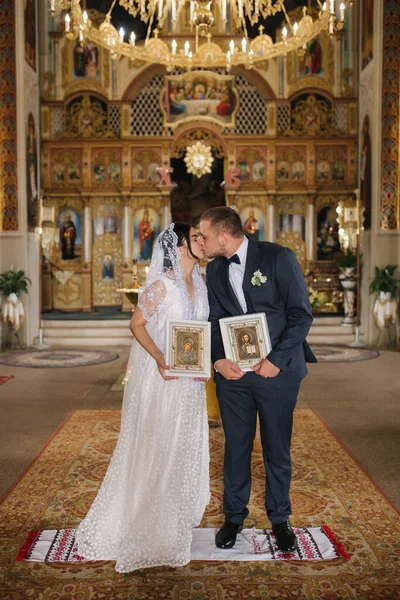 Noivo e noiva após cerimônia de casamento na igreja beijar uns aos outros — Fotografia de Stock