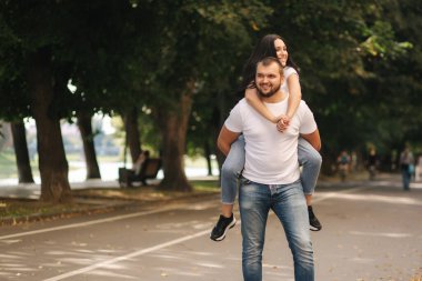 Güzel Gilr erkek arkadaşının sırtına bindi ve ona sarıldı. Mutlu gülümseyen çift şehirde vakit geçiriyor.
