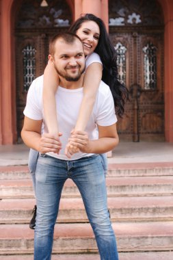 Güzel Gilr erkek arkadaşının sırtına bindi ve ona sarıldı. Mutlu gülümseyen çift şehirde vakit geçiriyor.