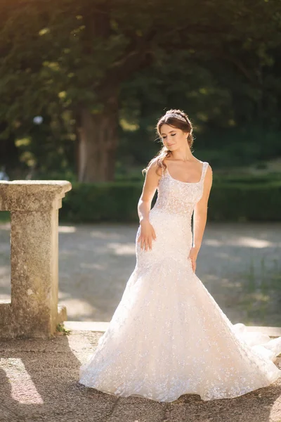 Modelo de noiva jovem atraente em belo vestido de noiva andando no parque — Fotografia de Stock