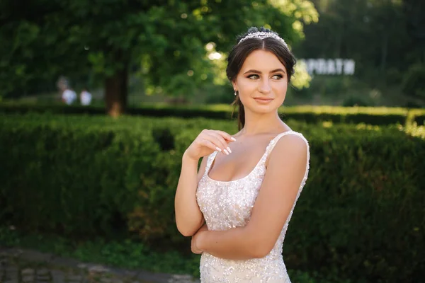 Modèle élégant en robe de mariée posant pour photographe à l'extérieur. Belle jeune femme avec maquillage de mode — Photo