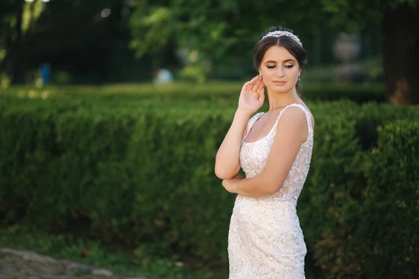 Modèle élégant en robe de mariée posant pour photographe à l'extérieur. Belle jeune femme avec maquillage de mode — Photo