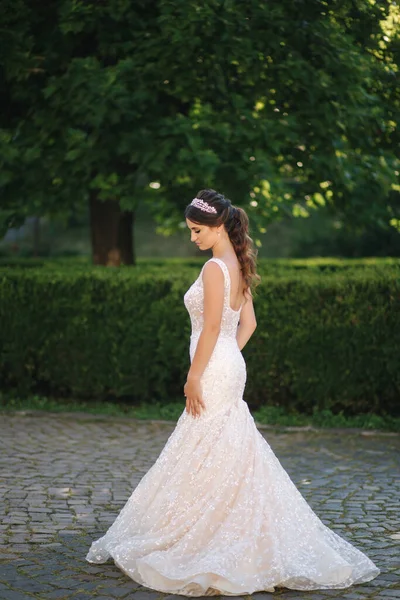 Modelo elegante em vestido de noiva posando para fotógrafo ao ar livre. Mulher bonita com maquiagem de moda — Fotografia de Stock