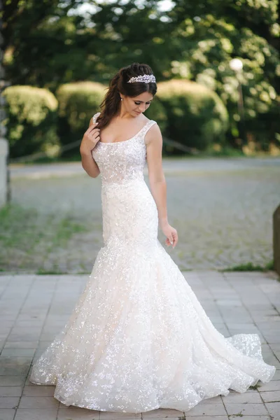 Modelo elegante em vestido de noiva posando para fotógrafo ao ar livre. Mulher bonita com maquiagem de moda — Fotografia de Stock