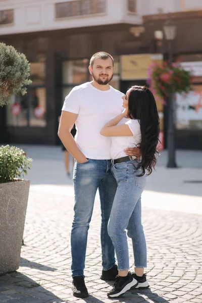 Pareja con estilo en mezclilla y camisetas blancas en el centro de la ciudad. Concepto de finales del verano — Foto de Stock