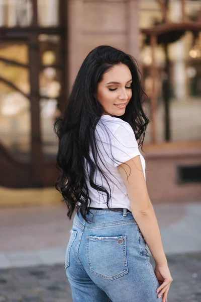 Portret van een mooie jonge brunette in een wit t-shirt. Mooie make-up — Stockfoto