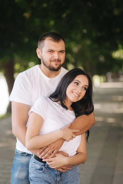 Pohledný muž se svou nádhernou přítelkyní. Šťastný pár kráčející po nábřeží. Zelené pozadí — Stock fotografie