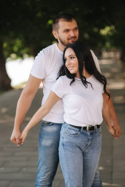 Schöner Mann mit seiner wunderschönen Freundin. Glückliches Paar, das entlang der Embabkment geht. Grüner Hintergrund — Stockfoto