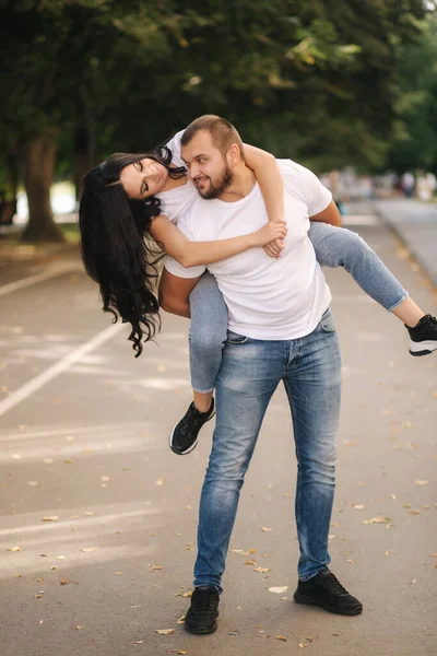 Krásná Gilr vyšplhala na svého přítele a objala ho. Šťastný usmívající se pár tráví čas ve městě — Stock fotografie