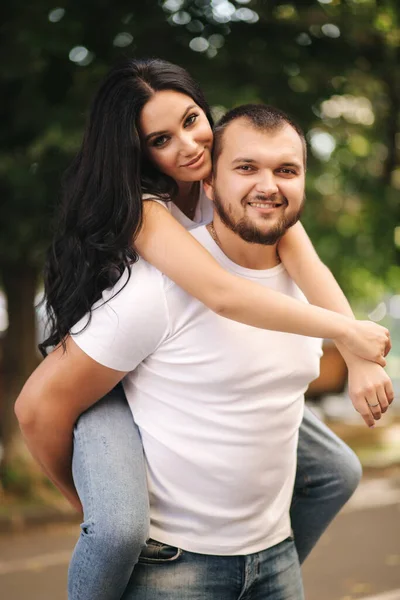 Beautiful gilr climbed on her boyfriend back and hug him. Happy smiled couple spend time in city — Stock Photo, Image
