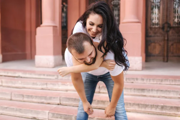 Hermosa Gilr se subió a su novio y lo abrazó. Feliz pareja sonriente pasar tiempo en la ciudad —  Fotos de Stock