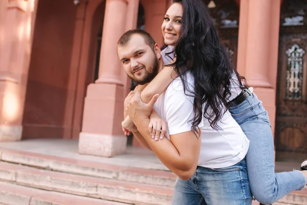 Hermosa Gilr se subió a su novio y lo abrazó. Feliz pareja sonriente pasar tiempo en la ciudad —  Fotos de Stock