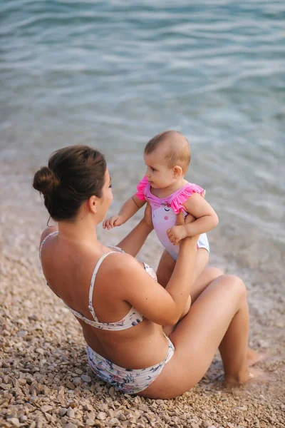 Baby Madchen Sitzen Auf Mamas Knien Am Strand Junge Schone Mutter Mit Ihrem Sussen Baby Mothe Und Tochter Im Schweineanzug Frau Aussenbereich Stock Photo 291574600