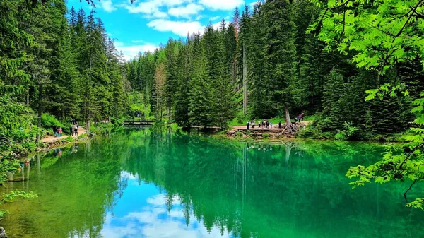Lago di Braies, Güney Tyrol, İtalya - 6 Haziran 2024: Tanınmayan turistler Dolomitler 'deki turkuaz bir gölün etrafında geziniyorlar