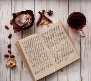 bir fincan çay, kamera, tarçın, baharat, kek, süt, ekmek, Yeşiller, çörek, çikolatalı çörek, marmelat, pembe somun ile masada pişirme, kitap, kek, muffin