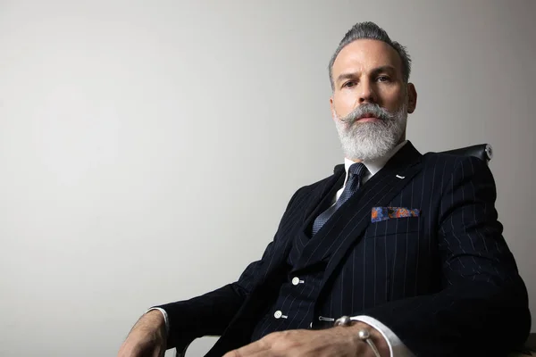 Portrait of positive bearded gentleman wearing trendy suit over empty gray background. Copy Paste space. Studio shot — Stock Photo, Image