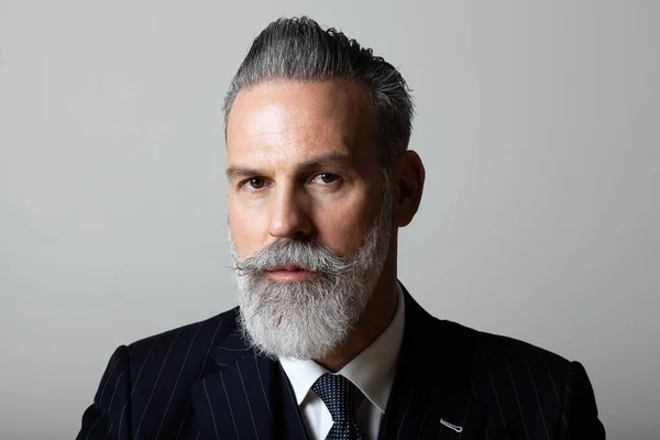 Porträtt av eleganta mellersta åldern skäggiga gentleman bär trendiga suit över tomma grå bakgrund. Affärsidé för Studio skott, mode. — Stockfoto