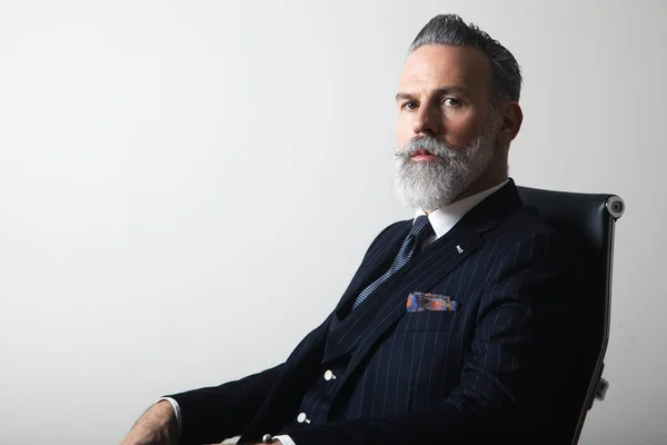 Portrait of positive bearded middle aged gentleman wearing trendy suit over empty gray background. Copy Paste space. Studio shot — Stock Photo, Image