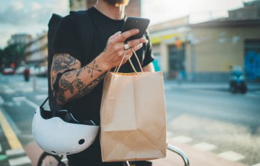 Kurye Bisiklet teslimat yemek servisi evde. Dövmeli adam kurye teslimat adresi şehirde bulmak için cep telefonu bir harita app kullanma