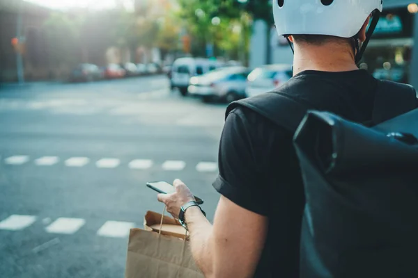 Man courier met behulp van een kaart app op mobiele telefoon te vinden van het adres van de geadresseerde in de stad. Anoniem Courier levering foodservice thuis. — Stockfoto