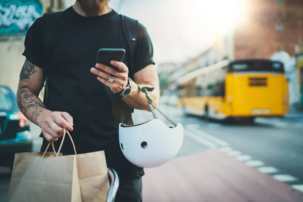 Wytatuowany mężczyzna kuriera za pomocą aplikacji mapy na telefonie komórkowym znaleźć adres dostawy w mieście. Kurier rowerowy dostawy usług gastronomicznych w domu. — Zdjęcie stockowe