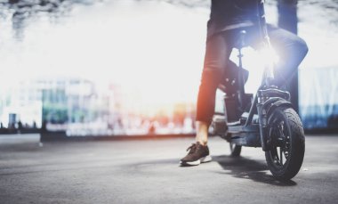 Elektrik kentsel ulaşım. Genç adam bir şehir merkezinde onun elektrikli scooter Bisiklete binmek hazır.