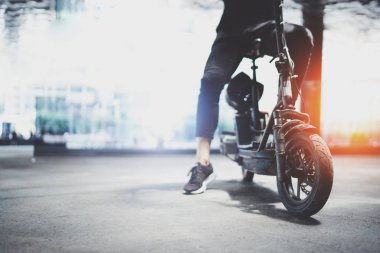 Elektrik kentsel ulaşım. Genç adam bir şehir merkezinde onun elektrikli scooter Bisiklete binmek hazır.