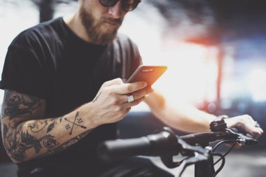 Sakallı dövmeli adam göndermek kısa mesaj için sürme sonra şehirde elektrikli scooter tarafından cep telefonu kullanarak güneş gözlüğü.