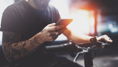 Sakallı dövmeli erkek tarafından şehrin elektrikli scooter sürme sonra smartphone kullanarak güneş gözlüğü.