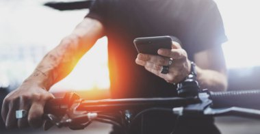 Smartphone elele ve şehrin elektrikli scooter sürme önce maps uygulaması kullanılarak hipster dövmeli adam.
