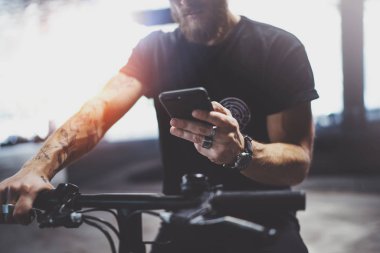 Dövmeli sakallı kaslı adam akıllı telefon elele ve kullanarak app sürme önce şehrin elektrikli scooter tarafından haritalar.