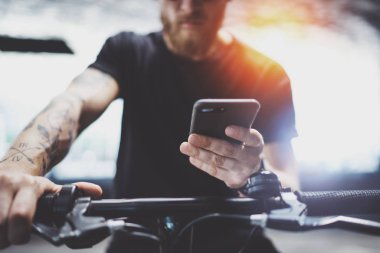Sakallı dövmeli erkek tarafından şehrin elektrikli scooter sürme sonra smartphone kullanarak güneş gözlüğü.