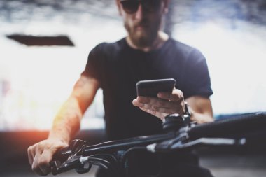 Sakallı kas dövmeli hippi tarafından şehrin elektrikli scooter sürme sonra smartphone kullanarak güneş gözlüğü. Yenilikçi ulaşım.