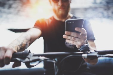 Sakallı kas dövmeli hippi tarafından şehrin elektrikli scooter sürme sonra smartphone kullanarak güneş gözlüğü. Yenilikçi ulaşım.