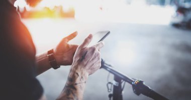 Cep telefonu elinde tutan ve sürüş yol güzergahı hazırlamak için harita app kullanarak dövmeli kaslı bir erkek. Kentsel şehir keşfetmek tarafından elektrikli scooter