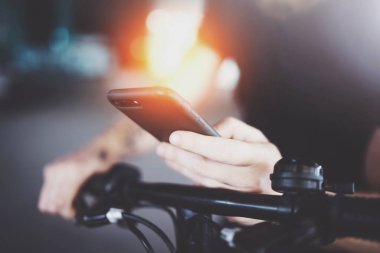 Cep telefonu elinde tutan ve sürüş yol güzergahı hazırlamak için harita app kullanarak dövmeli kaslı bir erkek. Kentsel şehir keşfetmek tarafından elektrikli scooter