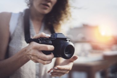 Casual elbise fotoğrafta bir retro kamerada günbatımı arka plan üzerinde gülümseyen güzel bir kız portresi kapatın