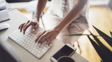 Kendine güvenen genç iş kadını office coworking, modern çalışma yerinde masaüstü bilgisayar kullanarak. Arka plan bulanık.