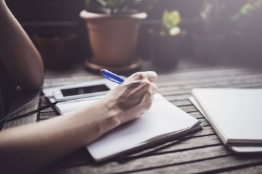 Caffee Teras ve not defterindeki not almak masada oturan genç iş kadını. Smartphone ve kağıt belgeler geçerli. Öğrenme Online öğrenci veya blogger kavramı.