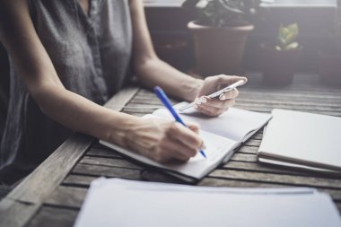 Caffee Teras ve not defterindeki not almak masada oturan genç iş kadını. Smartphone ve kağıt belgeler geçerli. Öğrenme Online öğrenci veya blogger kavramı.