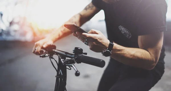 Tetovaný bokovky muž v ruce smartphone a používání aplikace mapy před jízdou elektrický Scooter ve městě. Inovativní doprava. — Stock fotografie