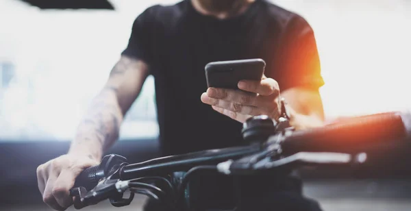 Tatoué mâle musculaire tenant le téléphone portable dans les mains et en utilisant l'application de carte pour préparer l'itinéraire routier. Découvrez la ville urbaine en scooter électrique — Photo