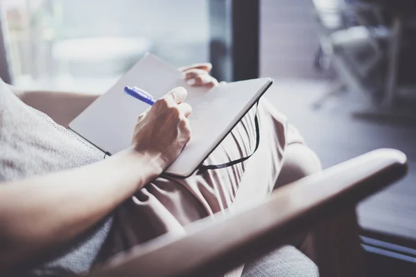 Trabajando en casa concepto. Joven mujer de negocios escribiendo y tomando notas mientras se relaja sentado en silla de confort en casa. Preparación de planes para la próxima semana — Foto de Stock