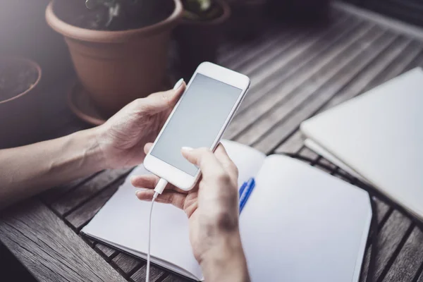 Ung affärskvinna sitter vid bord i caffee terrass och ta anteckningar i anteckningsboken. På bordet är smartphone och papper dokument. Studenternas lärande online eller blogger koncept. — Stockfoto