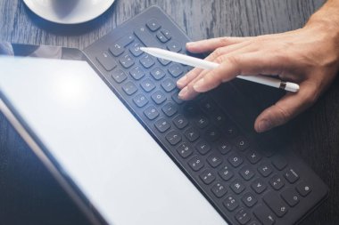 Ofiste çalışan ve elektronik kalem aygıtı kullanarak adam. Erkek el elektronik tablet klavye rıhtım istasyon yazarak closeup görünümü.