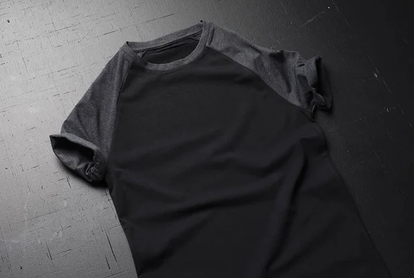 Ein sauberes gefaltetes Vintage-T-Shirt liegt auf einem schwarzen Holztischhintergrund. Frontansicht amerikanischer Hipster-Retro-Klassiker. — Stockfoto