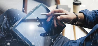 Tablet el üstünde tutan ve ofiste çalışırken elektronik kalem kullanarak iş adamı. Dijital diyagram, grafik arabirimleri, sanal ekran bağlantıları simgesi kavramı. Geniş format.